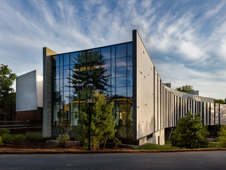 A glass-clad Integrated Science Commons nestled in a wooded area.