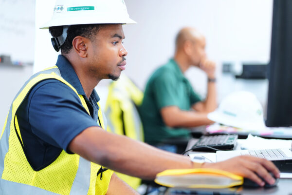 A hard hat-wearing professional engaged in computer-based tasks.
