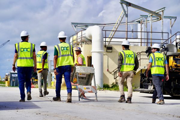 Several men walking on a job site with DOC high-vis vests.