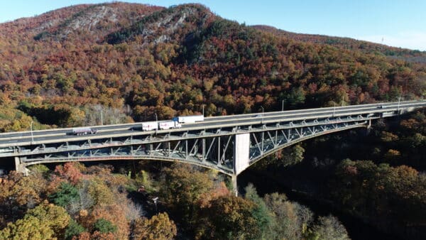 Transportation concept - trucks driving on a bridge in the mountains.