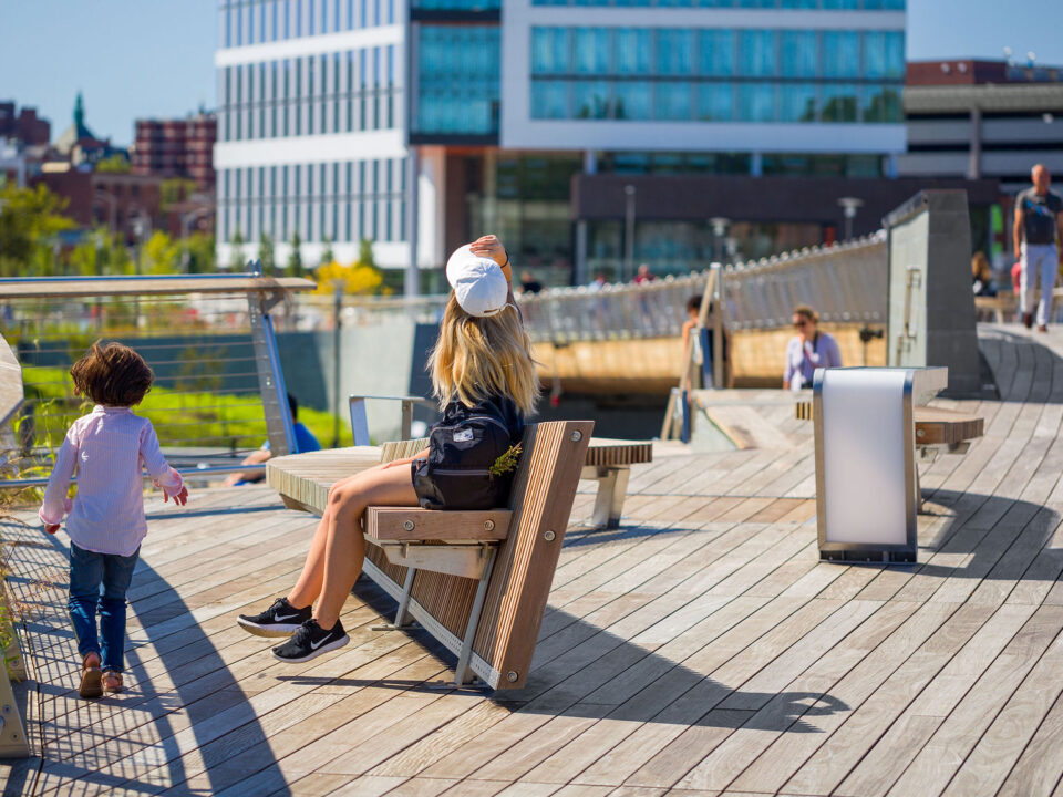 A woman and a child are sitting on a bench on the Michael S. Van Leesten Memorial Bridge.