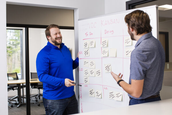 Two men in front of a Kanban board planning a Lean project.