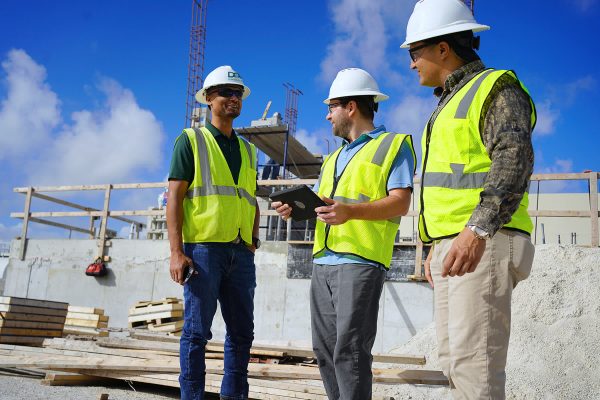 Three men conducting construction services on site.
