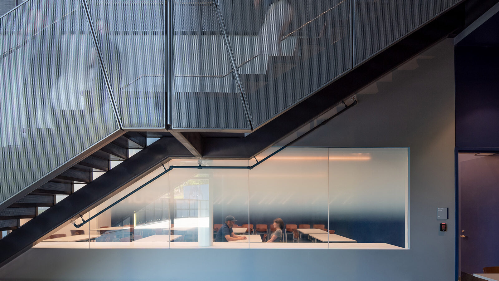 An office located within the Husky Athletic Village and Rizza Performance Center, featuring a glass staircase and benches.