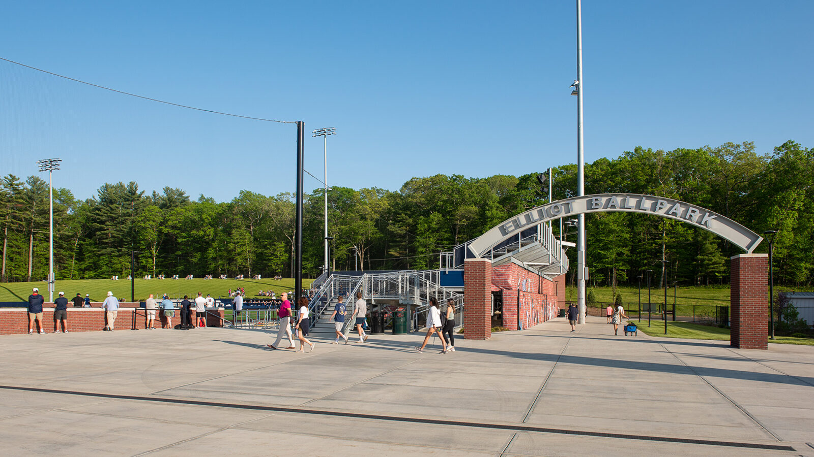 A group of people standing in front of the Husky Athletic Village baseball field.
