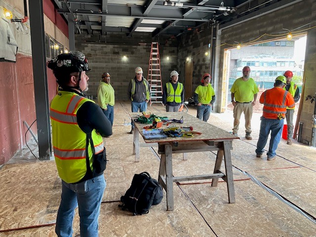 A team of construction workers demonstrating commitment to safety as they gather around a table.