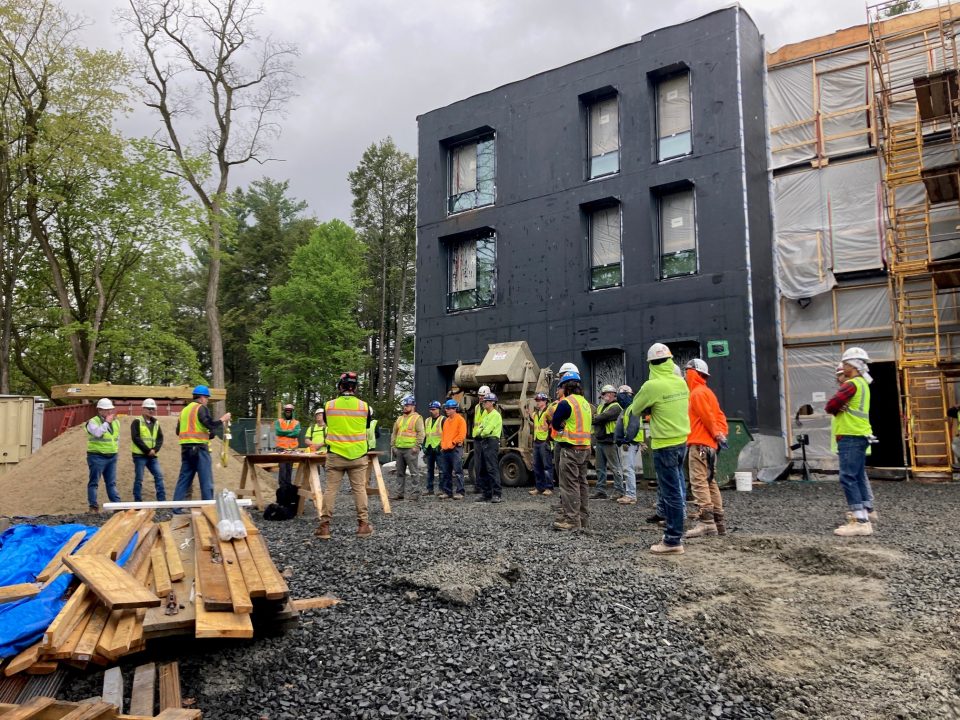 A group of construction workers demonstrating commitment to safety in front of a building.