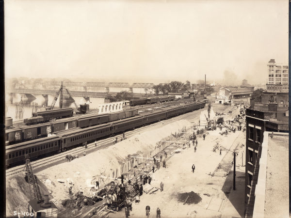 Old historic black and white photo of men working next to a train yard