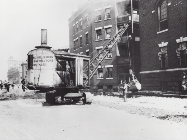 A historic black and white photo capturing the demolition of a building.