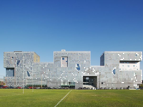 An impressive historical building with a soccer field in the background.