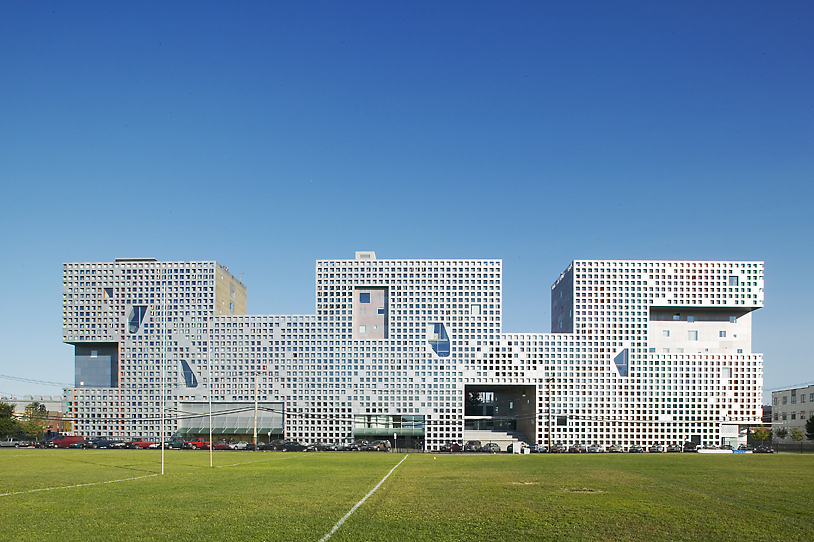 An impressive historical building with a soccer field in the background.